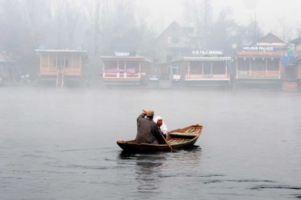 SRINAGAR, DEC 5 (UNI) A boatman rowing his Shikara taking across the famous Dal Lake an elderly woman amid dense fog as temperature dipped to minus 3.5 in Srinagar on Thursday. UNI SRN PHOTO 8