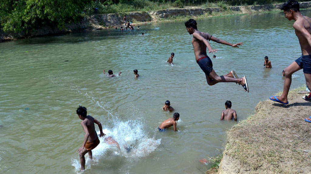 Amritsar: Boys cool themselves in a canal on a hot sunny day, on the outskirts of Amritsar on June 15, 2020. (Photo: IANS)