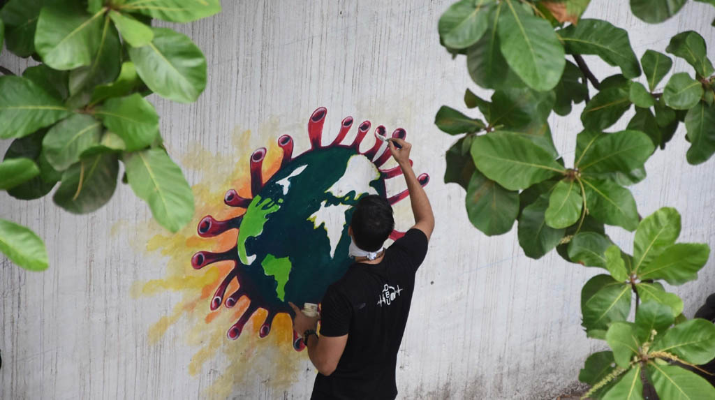Mumbai: An artist paints a wall graffiti of the 'Earth trapped in COVID-19 pandemic' in Mumbai on June 2, 2020. (Photo: IANS)